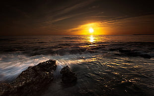 crashing waves on rocks during golden hour HD wallpaper