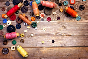 button and thread lot on brown wooden board