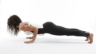 woman wearing white and black tank top and black leggings doing yoga
