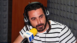 man wearing white-and-black pinstriped shirt in front of microphone