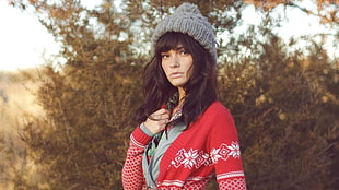woman wearing red and white printed sweater and gray bobble beanie while being photographed