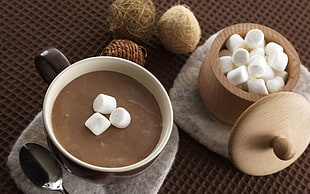 brown coffee in brown ceramic cup with three white marshmallows