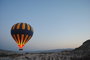 blue and orange hot air balloon on the air near mountain cliff