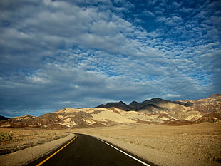 photo of road across mountains during cloudy daytime HD wallpaper