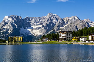 landscape photo of concrete buildings behind the mountains near the body of water, lake misurina
