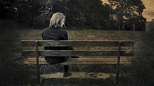man in black long-sleeved shirt sitting on brown wooden bench