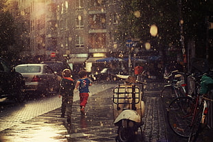 two children running during rainy day near street