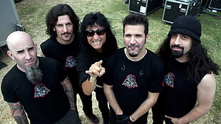 five men all wearing black shirts standing in green grass field during daytime
