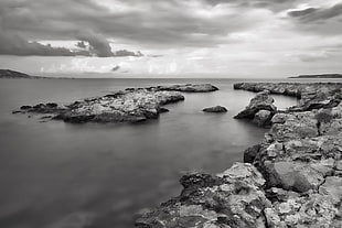 grayscale photography of rock formation near body of water