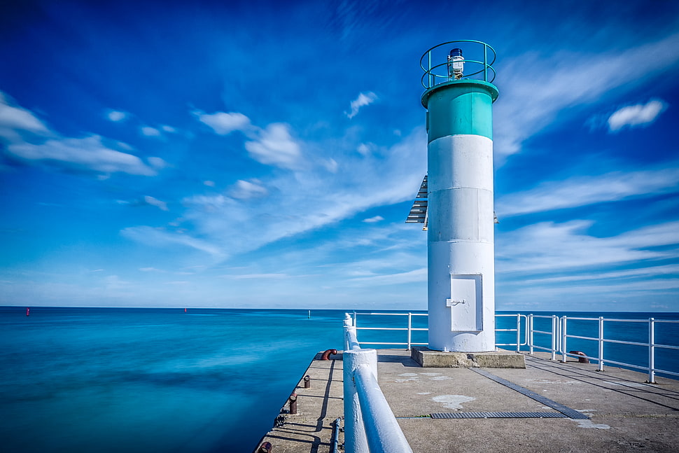 white and green lighthouse near body of water under white clouds and blue sky HD wallpaper