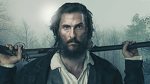 man with black coat holding rifle