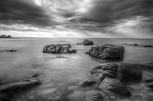 gray scale photo of rocks on body of water