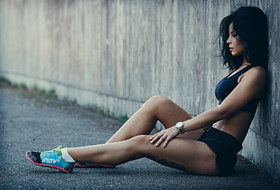 woman wearing black sports bra and black shorts sitting on floor