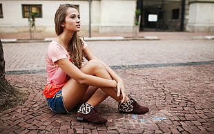 woman sitting on brown pavement