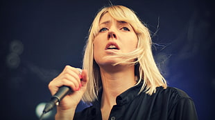 blonde hair woman holding a microphone
