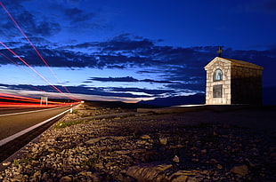 photo of white concrete chapel near road at night