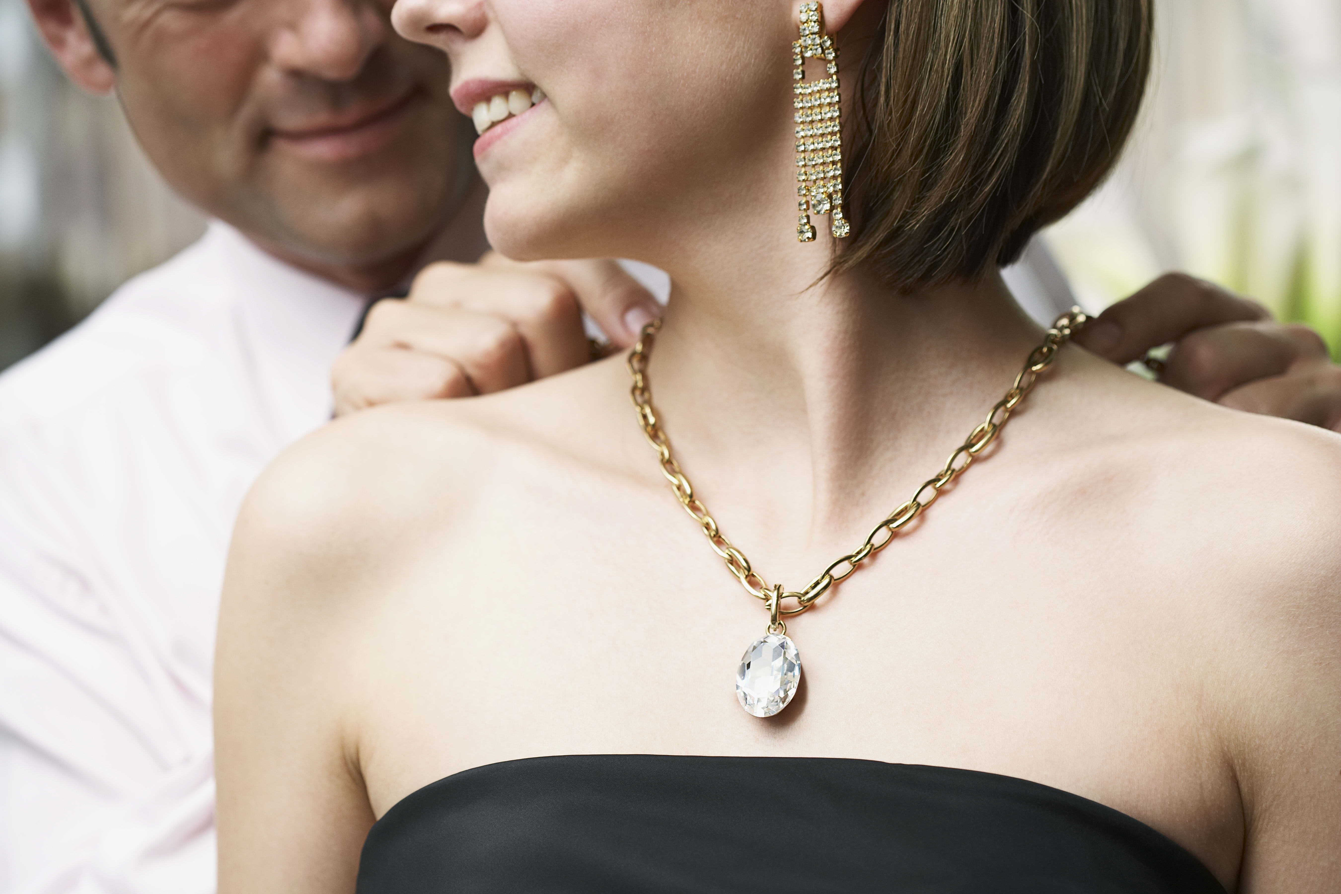 woman wearing black tube-type top with gold-colored chain link necklace with white gemstone pendant