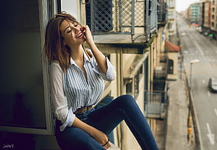woman in white dress shirt with blue denim jeans sitting on window HD wallpaper