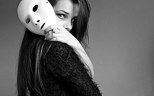 greyscale photo of woman in black top holding white mask