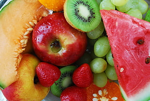 closeup photo of sliced watermelon with kiwi, apple, strawberry and grapes
