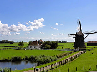 photo of windmill near white and brown house near body of water HD wallpaper