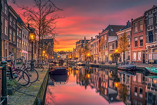 concrete buildings reflecting on canal with boats during golden hour HD wallpaper