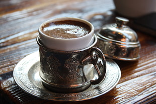 stainless steel teacup filled with coffee placed on top of table, turkish