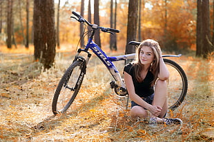 woman wearing black shirt sitting at the back of gray Stels mountain bike