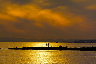 silhouette of two person on island during sunset HD wallpaper