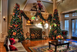 two giant green christmas tree beside fireplace