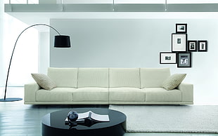white fabric 4-seat sofa in front of black collage photo frame