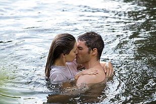 man and woman kissing in body of water during daytime