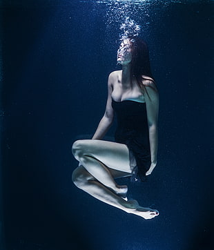 woman in black sweetheart dress drowning  in water