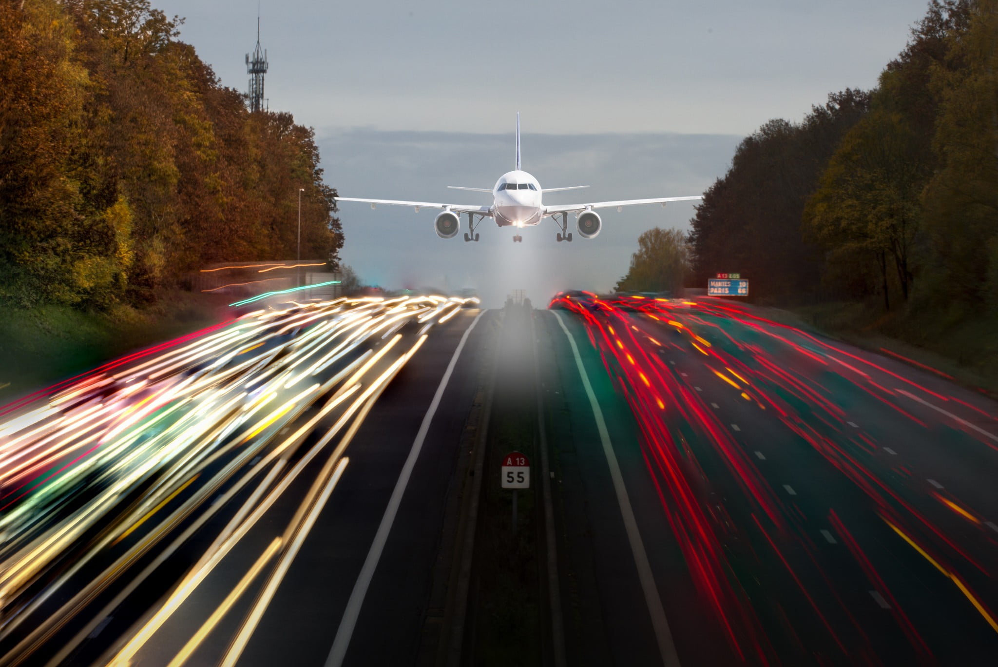 time lapse photo of white commercial plane above road with cars on street