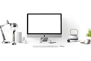 silver iMac on desk beside chrome desk lamp and white and black ceramic kettle