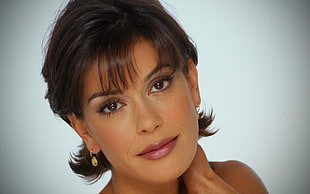 woman with short black hair and gold-colored earrings