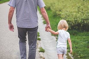 man wearing gray and black shirt holding girl's hand while walking on street HD wallpaper