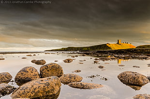 photo of brown stones on body of water, dunstanburgh HD wallpaper