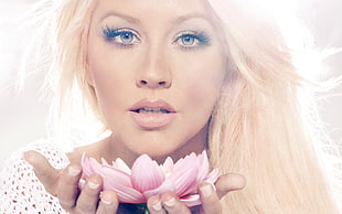 woman with blond hair with pink lotus flower on her hands