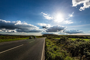 two car traveling on asphalt roadway besides green grass field under blue sky at daytime HD wallpaper