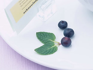 Blackberries with green leaf on white plate