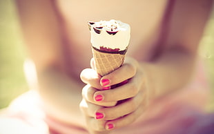 selective focus photography of woman holding ice cream