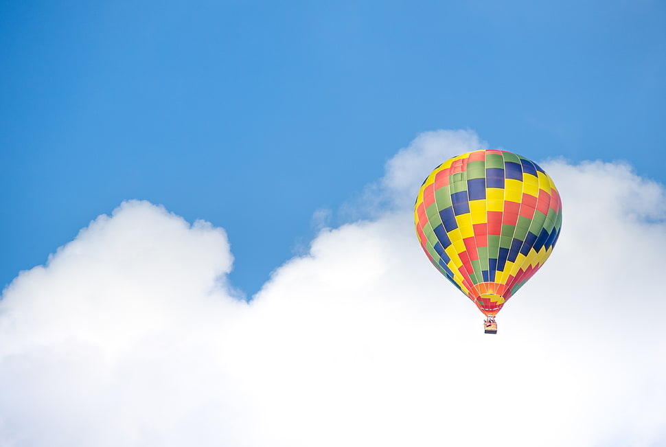 Yellow Blue and Green Hot Air Balloon Flying Near White Clouds HD wallpaper