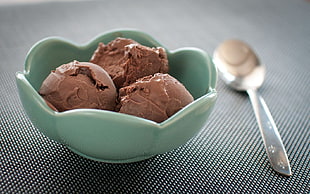 Chocolate ice cream on green ceramic bowl with stainless steel spoon