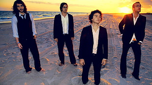 four member of boy band on sand