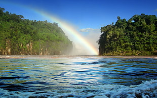 photo of two islands between rainbow