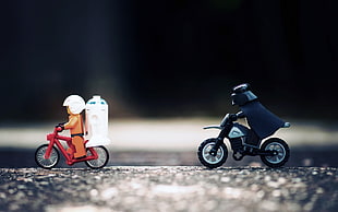 selective focus photography of two Star Wars characters toy riding motorcycle and bicycle
