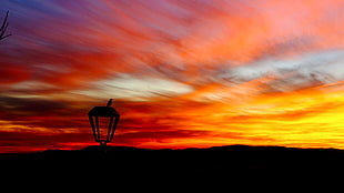 silhouette of outdoor post lamp under sunset sky