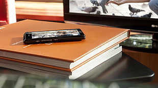 black android smartphone on orange book