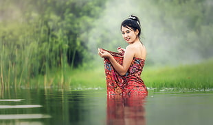 woman in red and blue blanket standing on body of water during foggy day